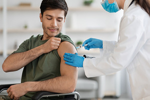 Closeup of disabled soldier getting immunization against coronavirus at clinic, a Photo by Prostock-Studio