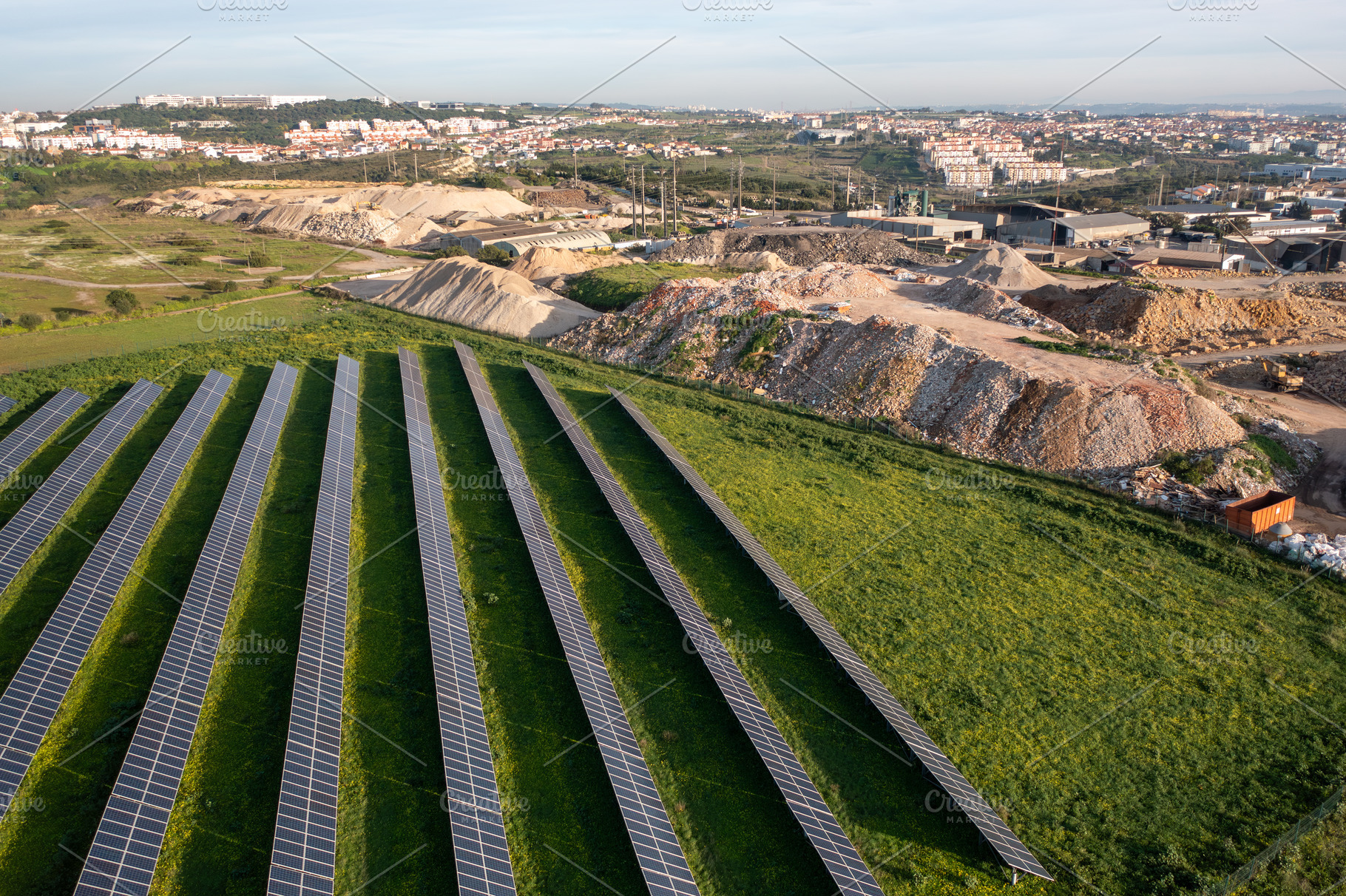 Solar panels dot an expansive green landscape near a construction site on a cle, a Photo by andreonegin market