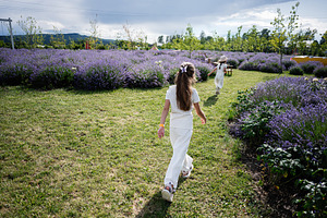 Young girls walking through a lavender field on a sunny summer day, a Photo by AS photostudio