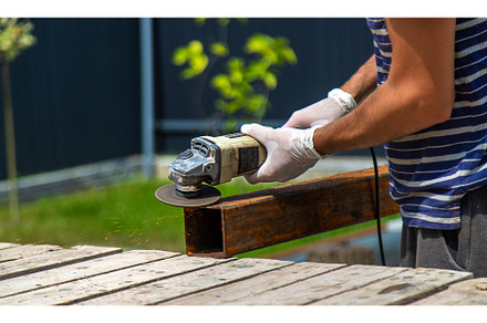 A man processes a metal pole, an Industrial Photo by yanadjana