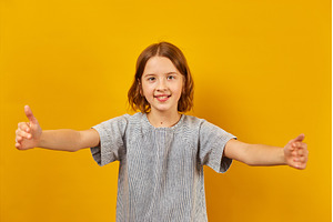 Cheerful girl giving thumbs up with, a Background Photo by IlliaBondarPhotography