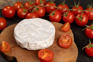 soft cheese with mold and ripe small red tomatoes, red round tomatoes on the ta, a Photo by rsoollAI