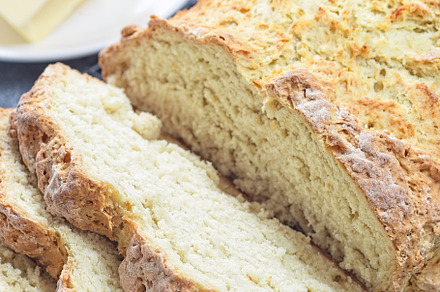 Freshly baked soda bread on cooling rack, sliced, with butter and honey in the
