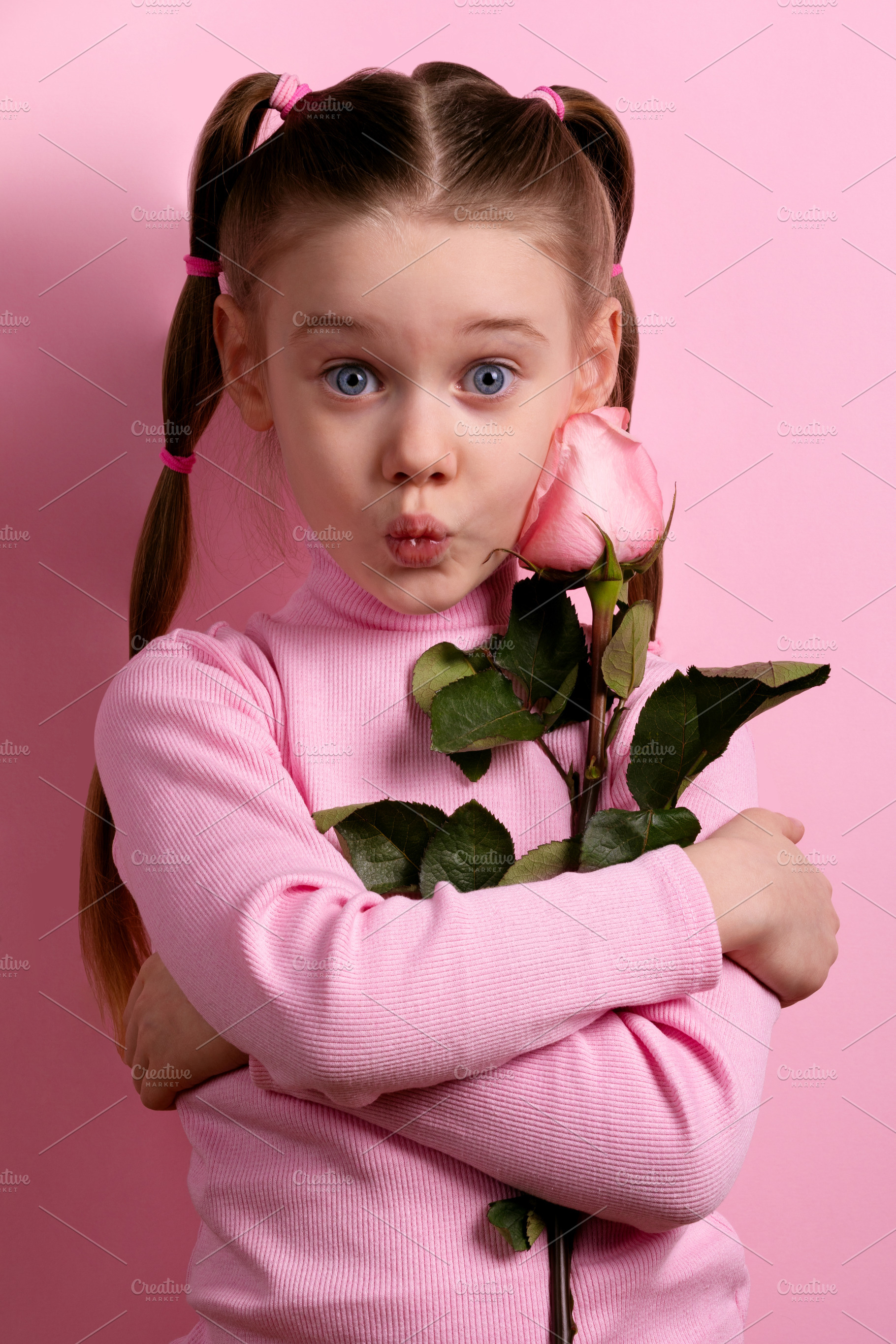 Cute young girl in pink with pigtails holding a rose and making, a Person Photo by Ales Munt