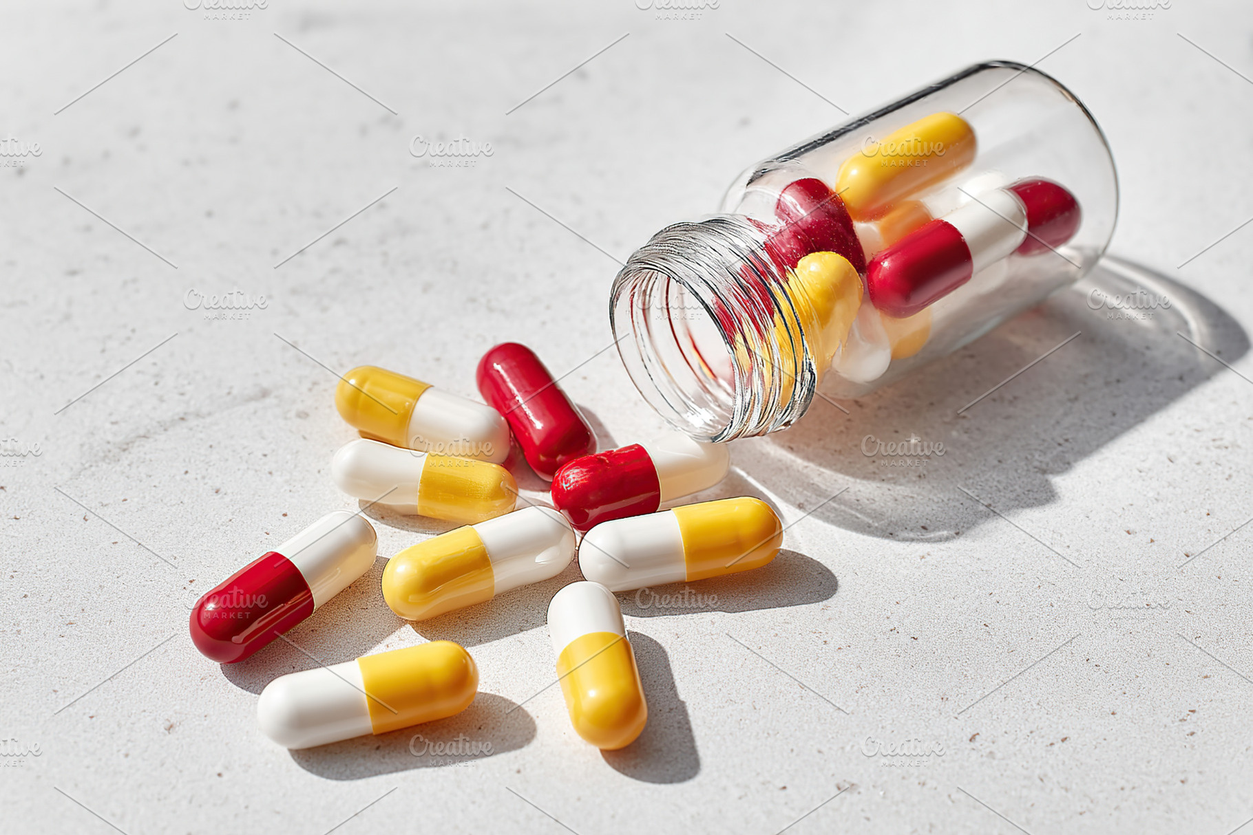 Small transparent pill and colorful capsules scattered from glass bottle on fla, a Health & Medical Photo by AlyaAnd