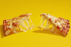 Pulling two slices of hot cheese pizza apart, showcasing the goo, a Photo by Studio ANNA