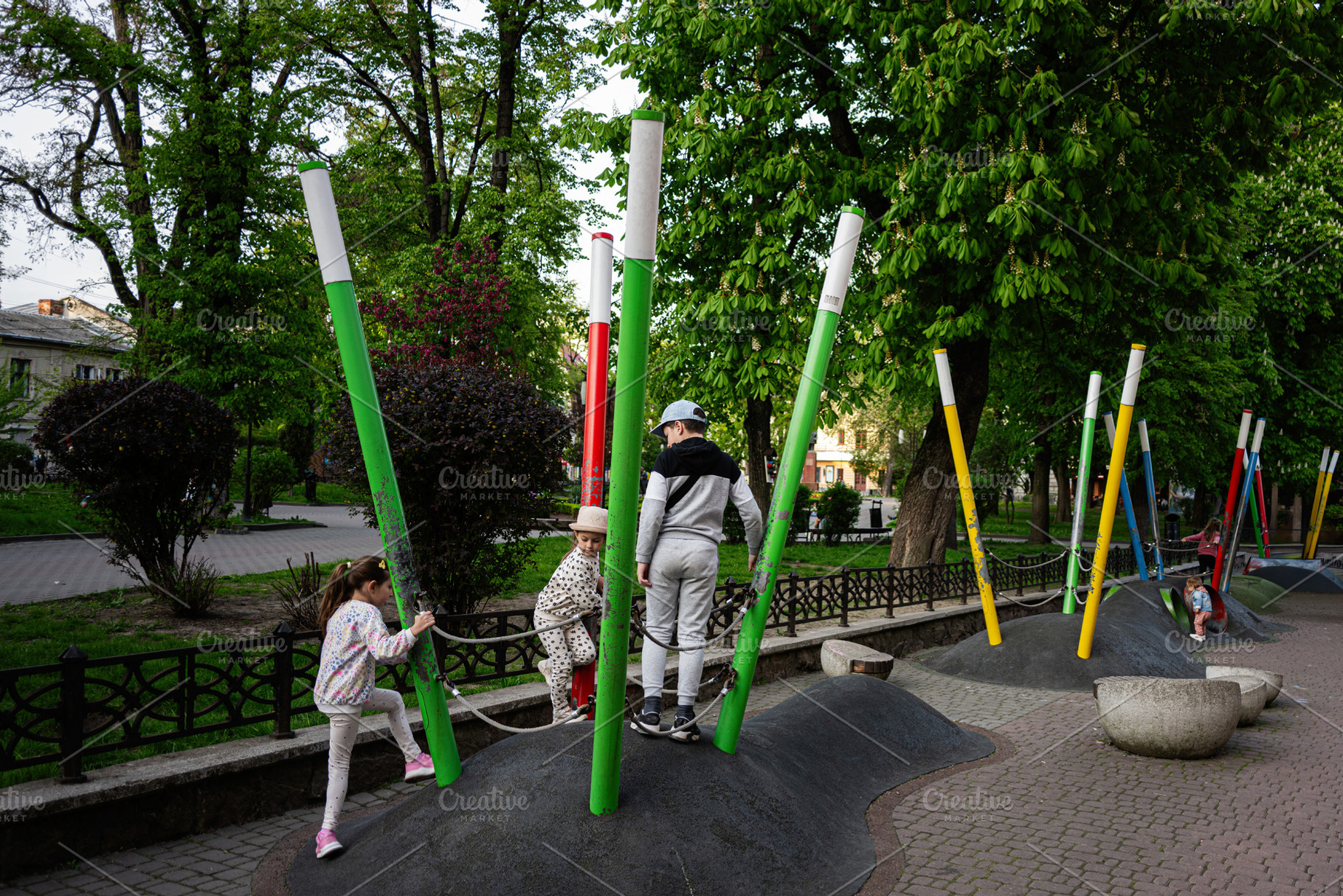 Children playing on a colorful outdoor playground in a park surrounded by trees, a Person Photo by AS photostudio