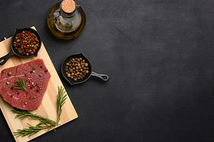 Raw piece of beef with spices pepper, rosemary sprig, salt and o, a Food & Drink Photo by ndanko