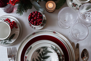 Elegant festive table setting with fine china, holly, berries, candles, and win, a Food & Drink Photo by Studio ANNA