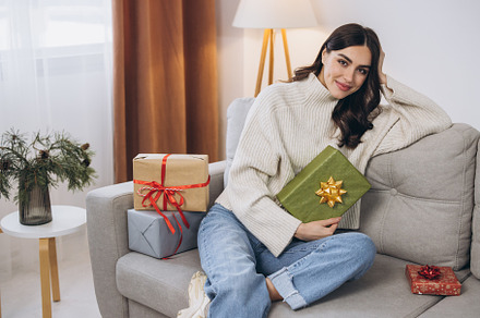 Beautiful happy woman unwrapping New Year or Christmas presents