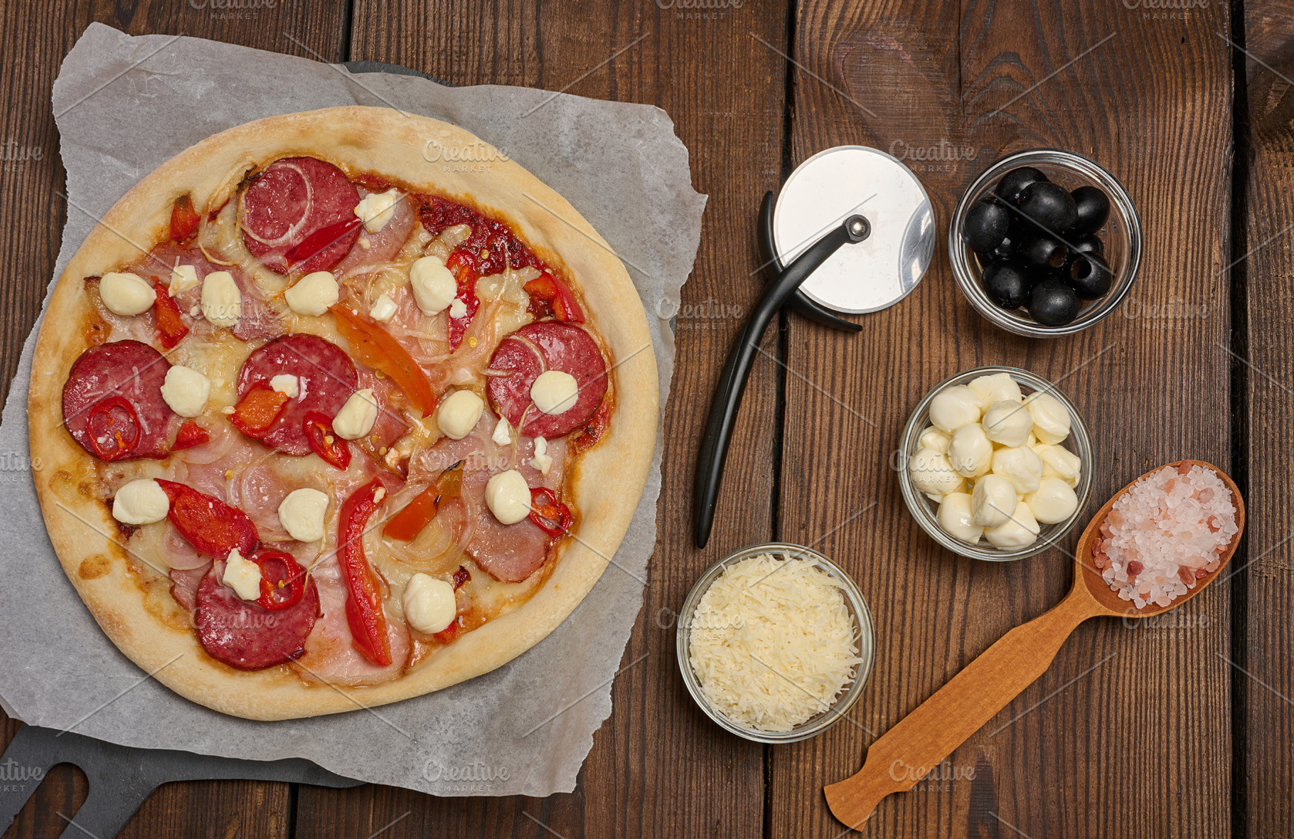 Pizza with salami, ham and mozzarella cheese on parchment, a Food & Drink Photo by ndanko