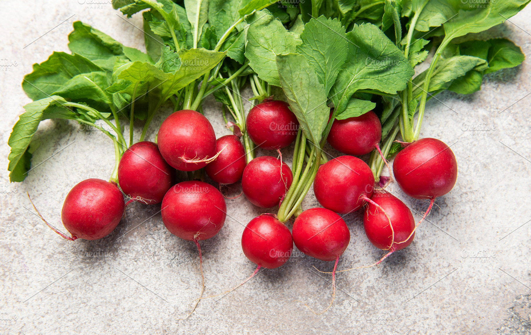 Fresh red radishes with green leaves on grey background, a Food & Drink Photo by Olena Rudo