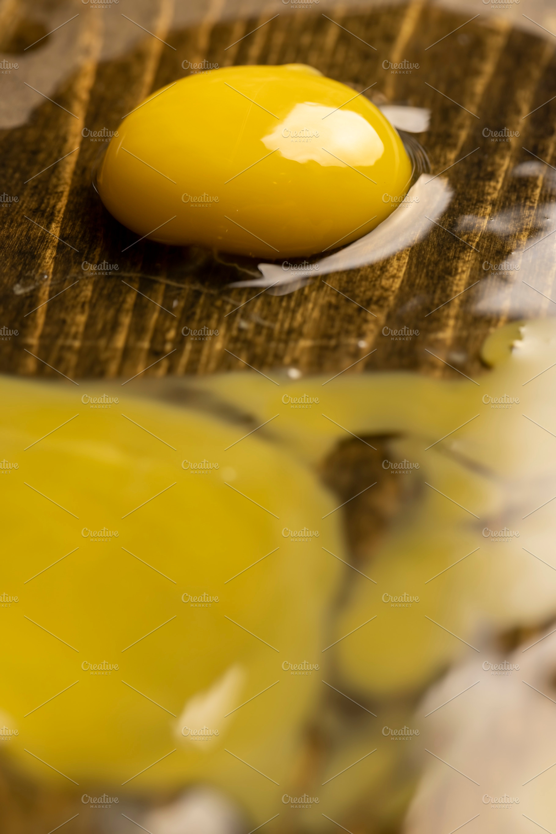 cracked chicken egg spreads on a black wooden board, side view, a Photo by rsoollAI