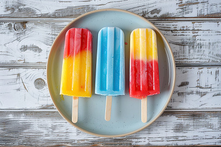 Colorful ice cream popsicles in plate on wooden background, a Food & Drink Photo by AlyaAnd