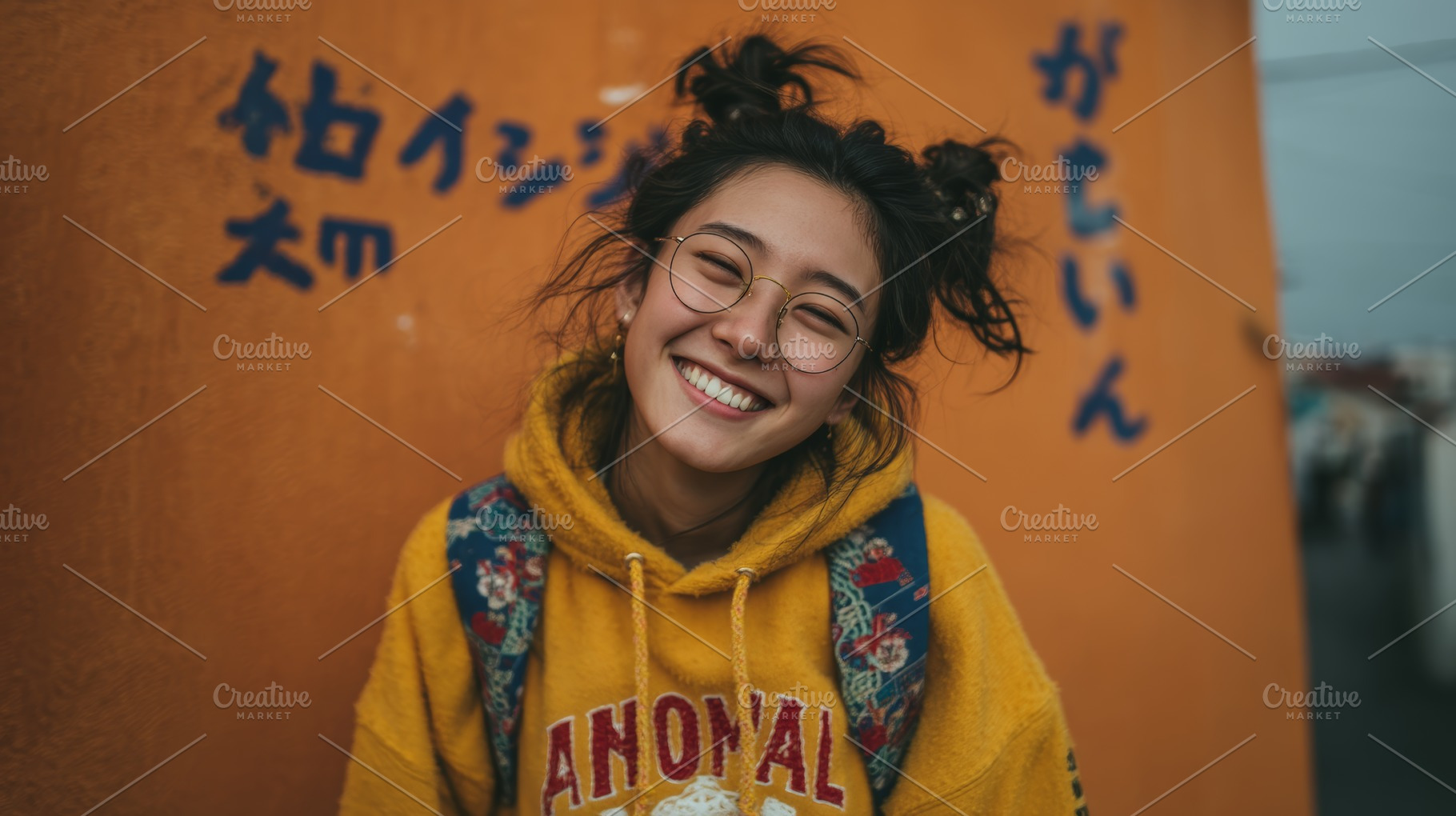 Young woman in yellow hoodie smiling against orange wall with backpack and glas, a Photo by AS photostudio