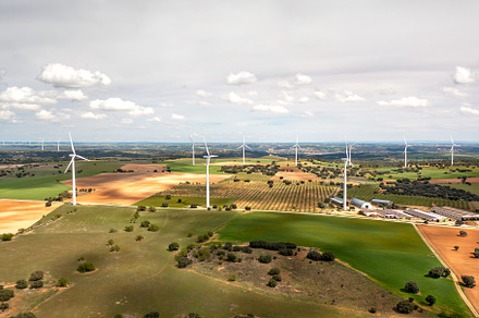 Wind turbines spinning over vast farmland with cloudy skies