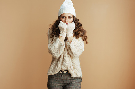 sad trendy woman against beige background warming hands, a Person Photo by Alliance Images