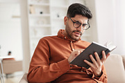Focused Arab man in glasses trying to read book, a Photo by Prostock-Studio (Thumbnail 1 of 2)