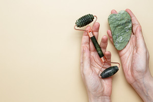 Female hands holding marble face roller and gua sha tools for skincare routine, a Photo by matucha