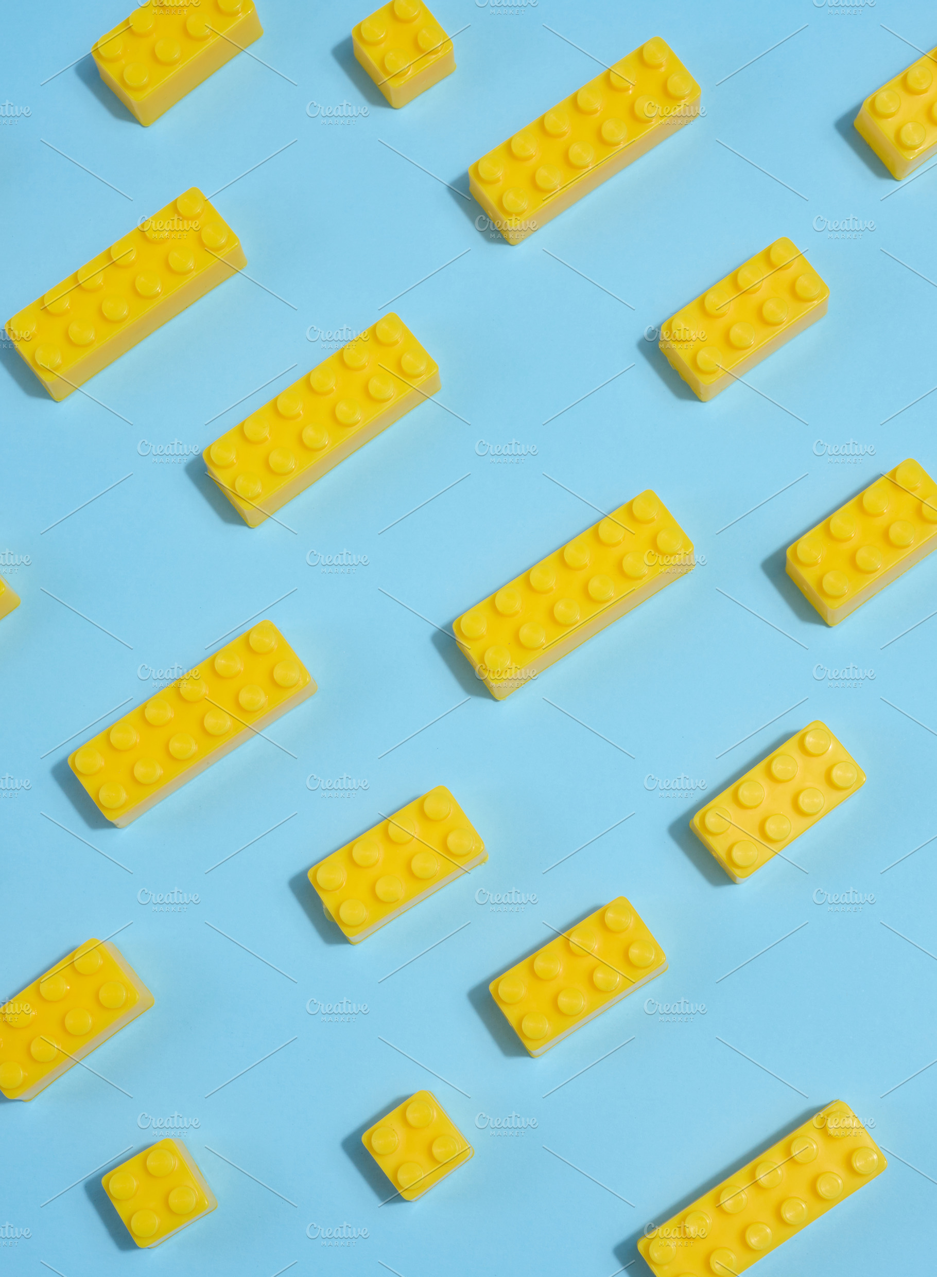 Scattered yellow plastic toy building bricks on a blue backgroun, a Background Photo by ndanko