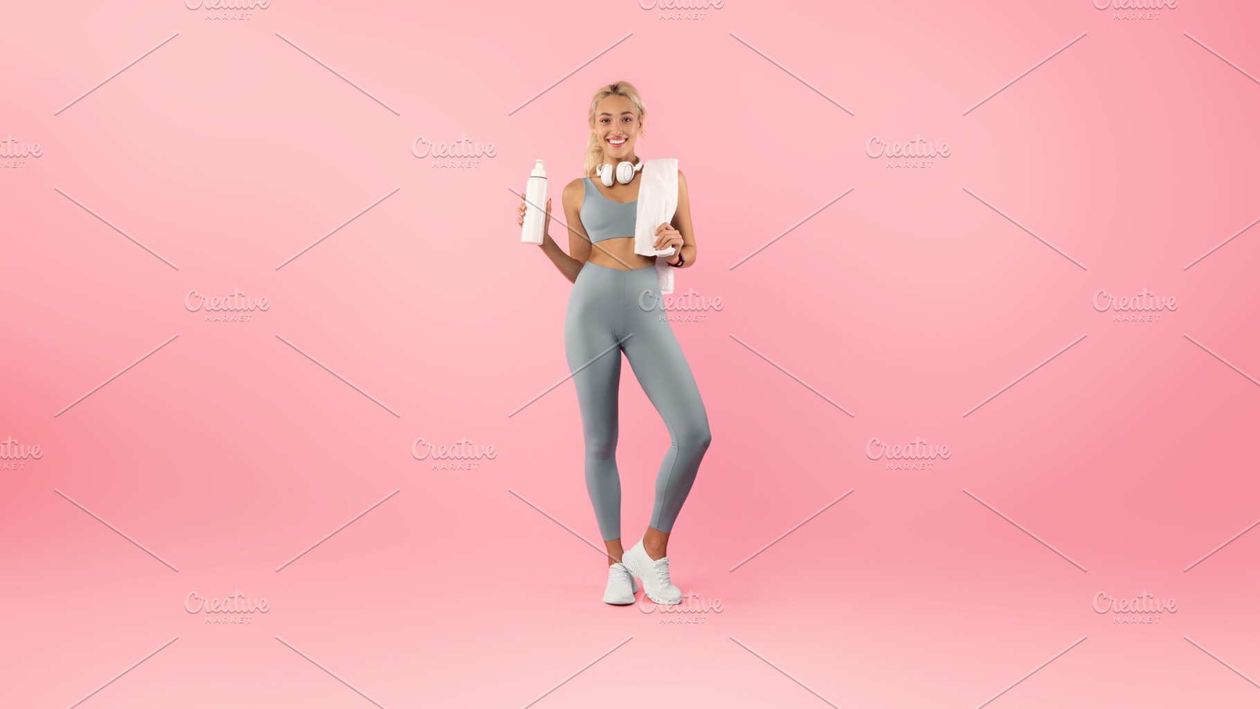 Sporty smiling woman posing at studio with water bottle, a Photo by Prostock-Studio