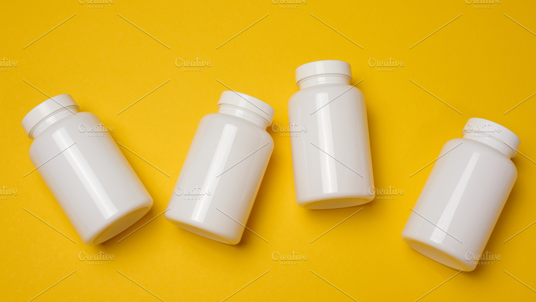 White plastic medicine jars on a yellow background, top view, a Health & Medical Photo by ndanko