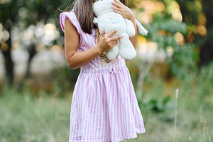 Cute little girl hugging plush toy bunny in summer park., a Person Photo by Rohan Photography