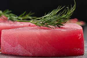 Raw piece of tuna with a sprig of dill on a black board, close u, a Food & Drink Photo by ndanko