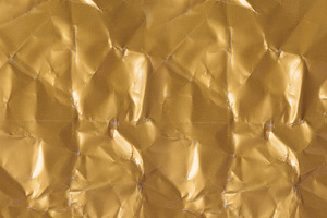 Seamless texture of crumpled golden paper with shiny folds