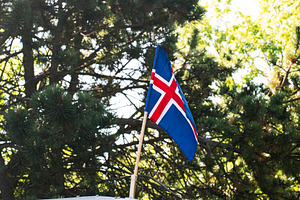 The Flag of Iceland Raised Vertically Against a Background of Scenic Greenery, a Photo by AS photostudio