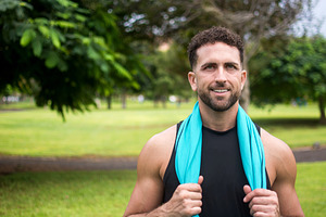 Athletic man holding blue towel around neck after outdoor workout, a Person Photo by etorres69
