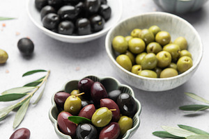 Assorted olives in decorative bowls on white surface, a Food & Drink Photo by Olena Rudo
