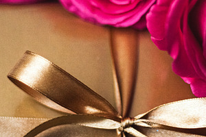 Gift box wrapped in golden paper with a satin ribbon bow and vib, a Photo by Studio ANNA
