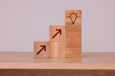 Wood, blocks and idea with light bulb icon for creativity, innovation and development with wooden cubes against studio background. Brainstorming, conclusion and motivation for growth, action or goal, a Photo by Peopleimages.com