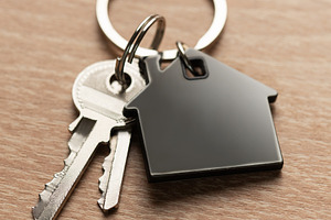 House keys with house shaped keychain on wood