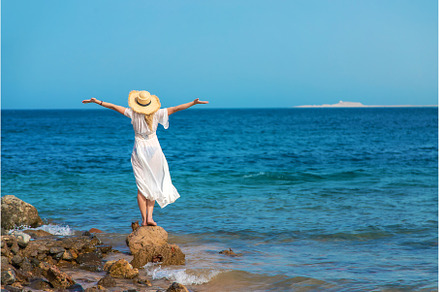 A woman in a hat looks at the sea, a Nature Photo by yanadjana
