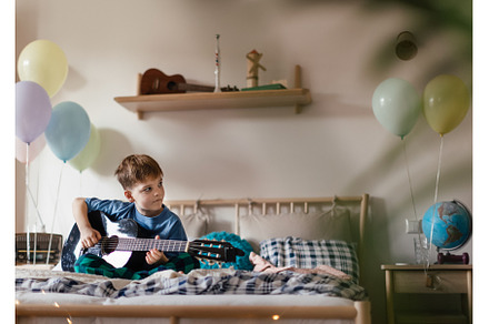 Happy boy playing on the guitar in, a School & Education Photo by HalfPoint