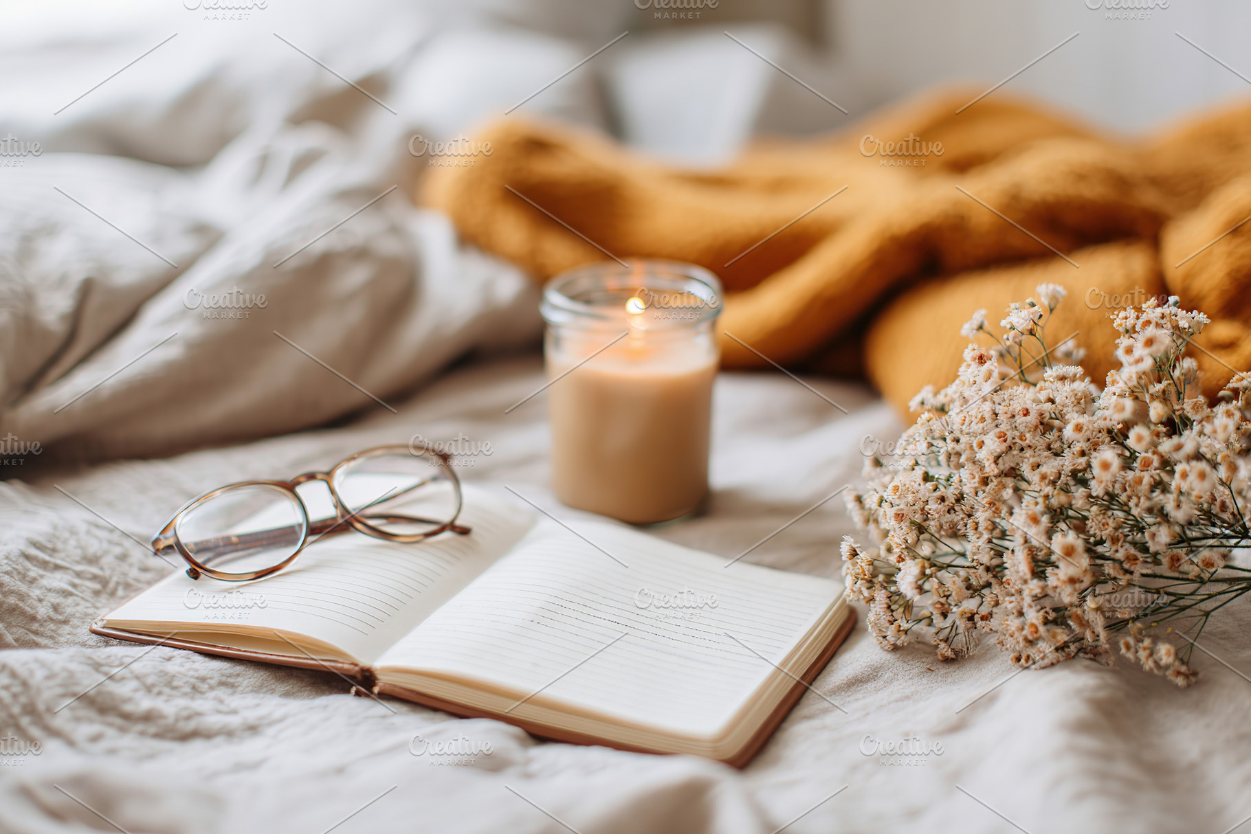 Handwritten letter resting on an unmade bed with a candle and flowers nearby, a Photo by AlyaAnd
