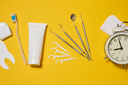 Dental floss in a case, white tube of toothpaste, dental instrum