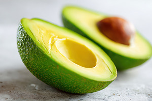 Fresh halved avocado with seed on wooden table, a Food & Drink Photo by AlyaAnd
