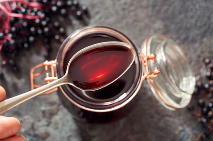 A spoon with black elder syrup with fresh elderberries, a Health & Medical Photo by Madeleine Steinbach