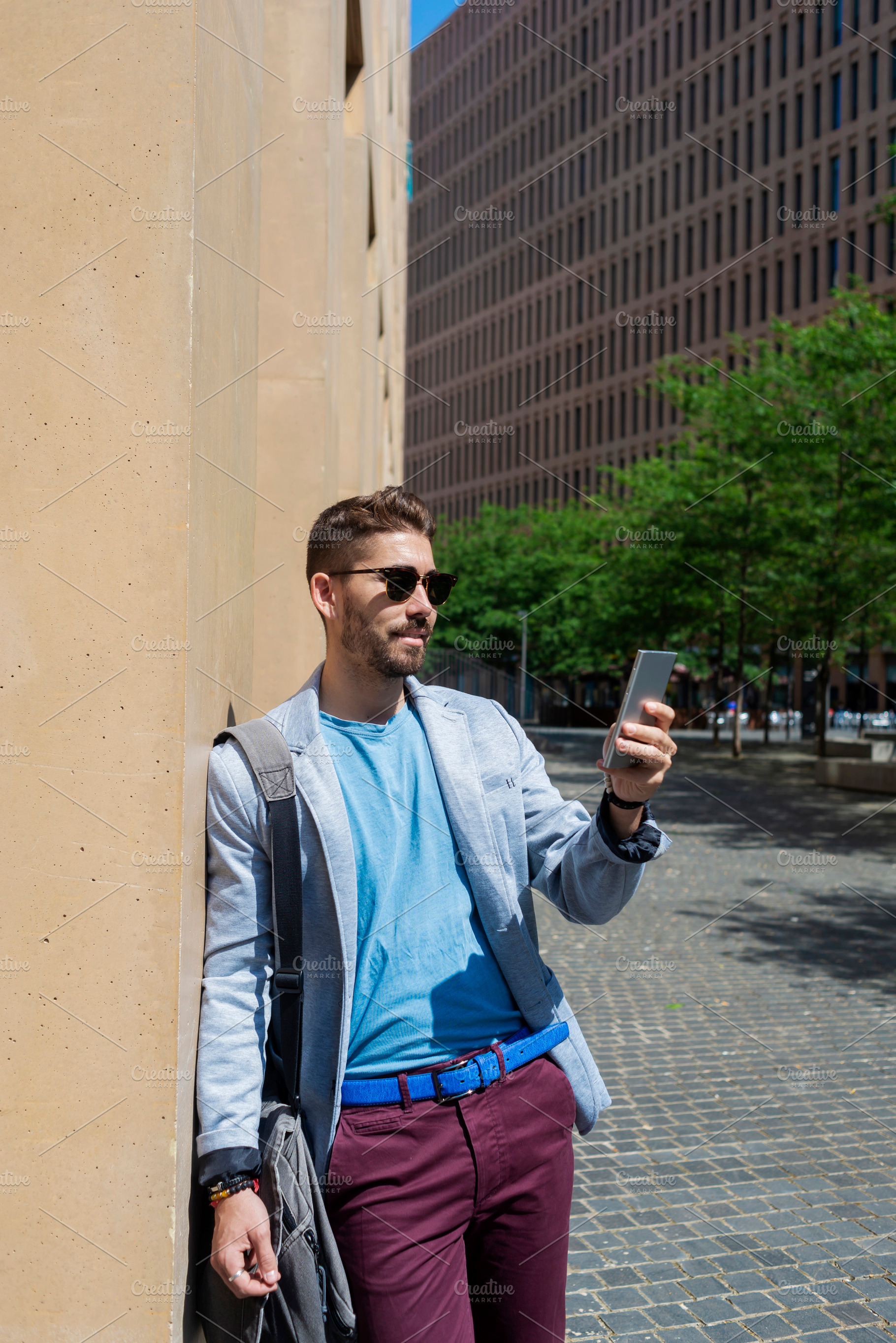 Handsome young man smiling when he is using his mobile phone, a Person Photo by RF Images