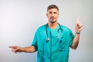 Doctor Pointing in Opposite Directions Smiling, a Person Photo by karrastock