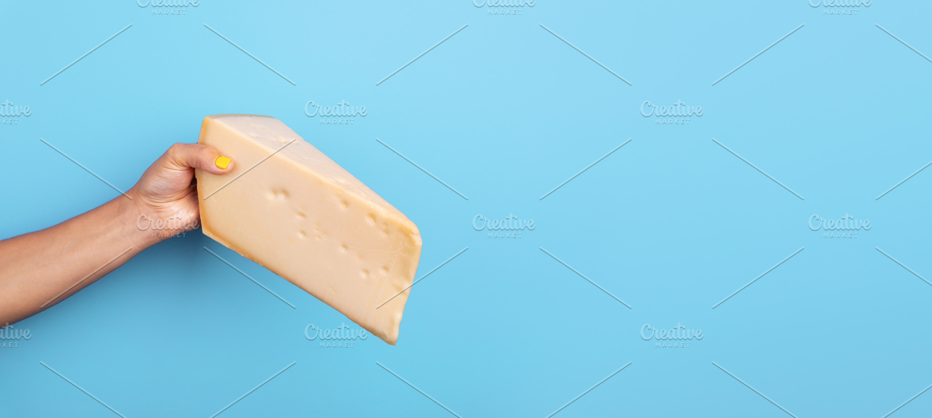 Female hand with yellow nail polish holding a large wedge of ch, a Food & Drink Photo by Ales Munt