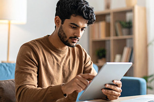 Young adult using a digital tablet to study at home, a School & Education Photo by DanFLCreativo