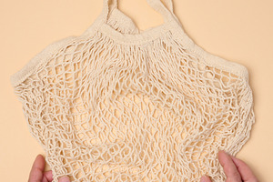 Empty reusable cotton mesh bag in female hands, a Person Photo by ndanko
