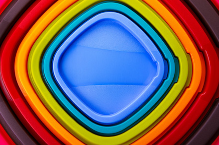 Overhead view of stacked plastic trays in vibrant rainbow colors