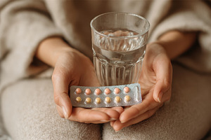 Woman holding pills and water health, a Photo by Pixeness Studio