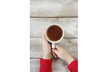 A cup of tea in the hands of a child, a Food & Drink Photo by yanadjana