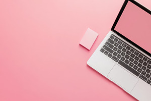 Laptop and pink notepad sit on pink, a Photo by Pavel_design